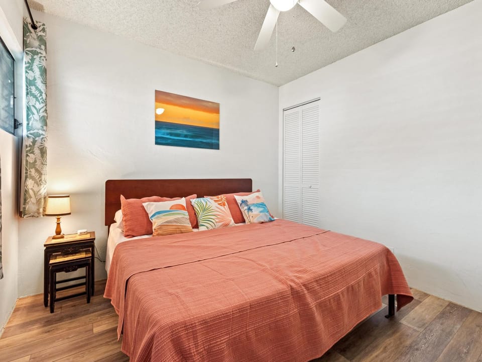 Your bright bedroom awaits with cozy coral bedding, tropical pillows, and a ceiling fan for your comfort. Unpack in the wardrobe and rest easy beneath artwork that sets a peaceful tone.
