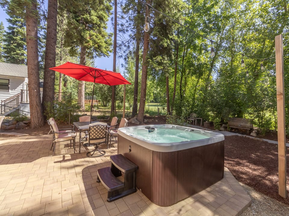 Soak in the hot tub under towering pines, dine al fresco beneath the red umbrella, and let the forest surroundings soothe your senses.