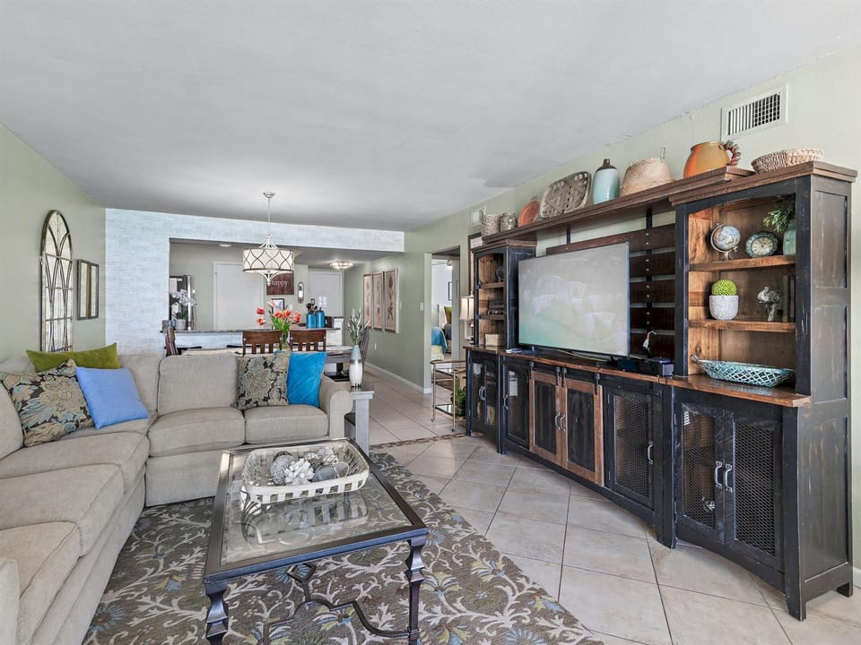 Relax in your spacious living area with plush sectional seating, entertainment center, and open layout flowing to the modern kitchen.