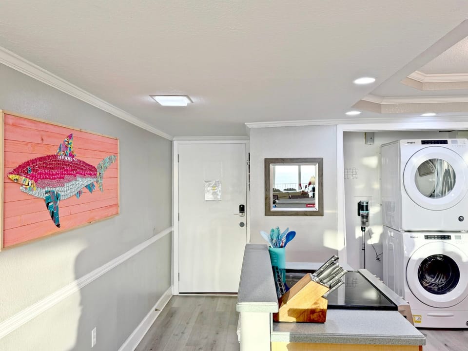 Your bright kitchen features full-size appliances and cheerful coastal artwork, with convenient in-unit laundry tucked nearby for ultimate comfort.