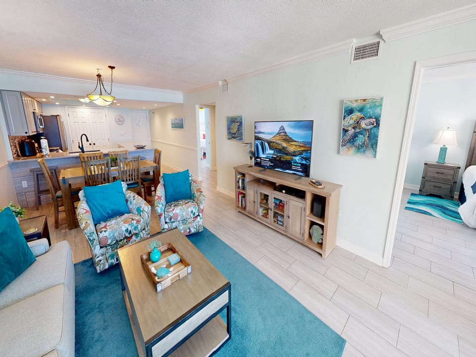 Relax in your bright, coastal-themed living space where ocean artwork and turquoise accents create the perfect beach vibe for your getaway.