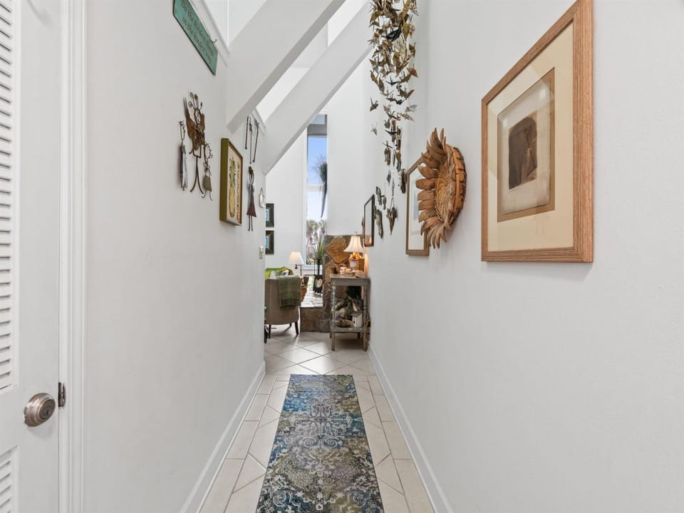 Step into your bright hallway adorned with curated artwork and tropical accents, leading you to comfortable living spaces filled with character.