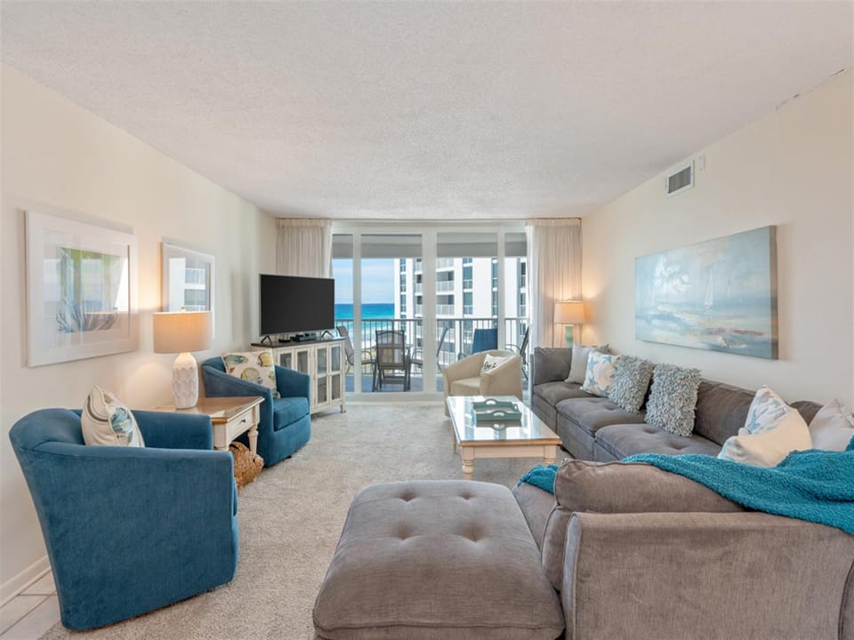 Relax in your ocean-view living room with plush seating, coastal decor, and balcony access to stunning sea views.