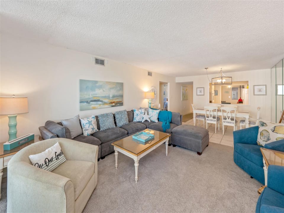 Your spacious living room flows seamlessly into the dining area, with coastal blues and comfortable seating perfect for gathering.