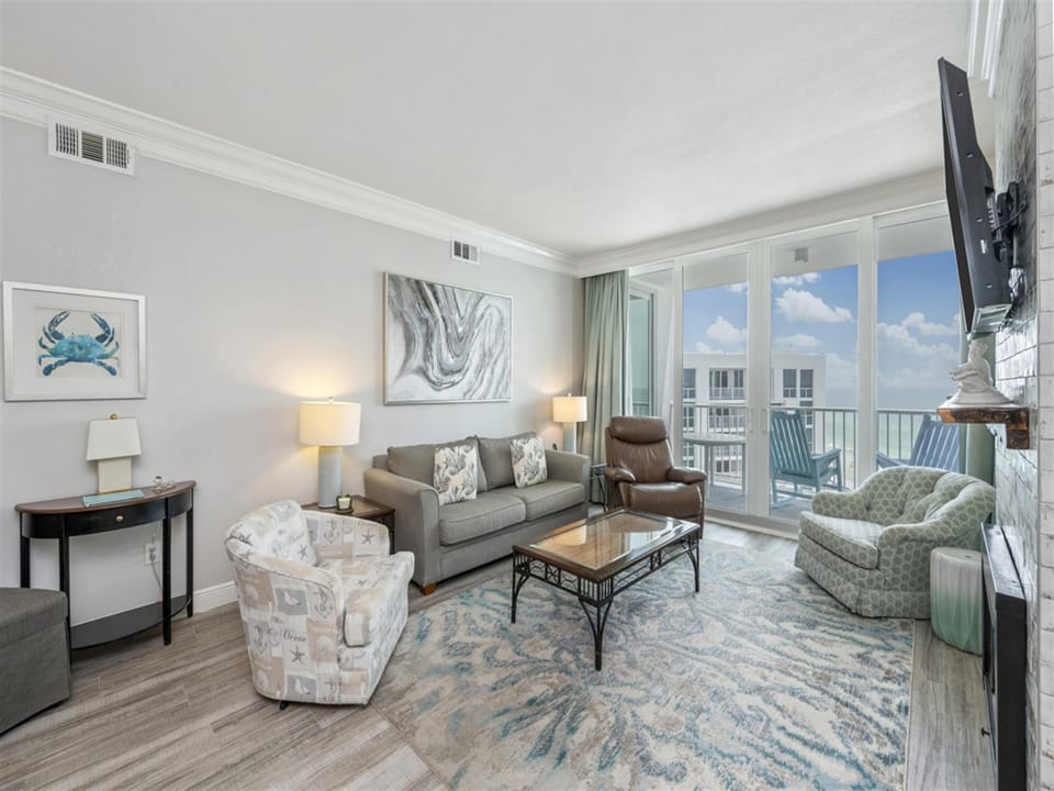 Relax in your bright coastal living room with ocean views through floor-to-ceiling windows and comfortable seating for your group.