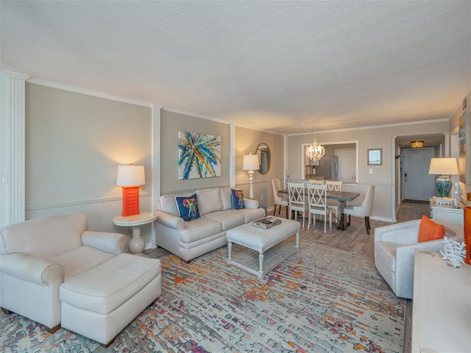 Sink into plush sofas and unwind in your spacious living room, where coastal artwork and pops of coral create a serene retreat.