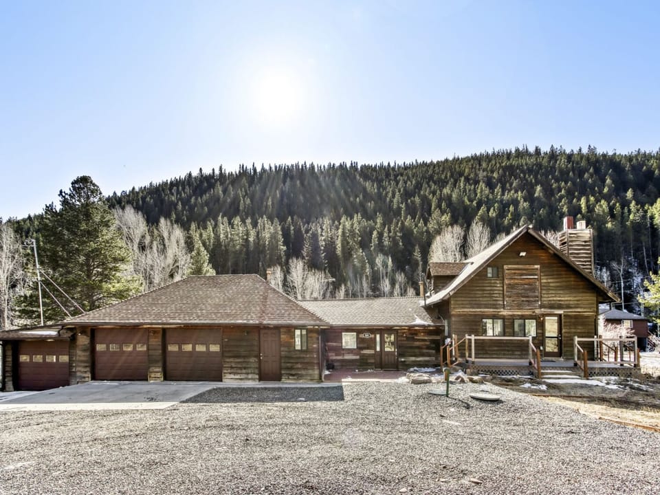 Mountain chalet nestled among snow-dusted forests with expansive parking and rustic wooden architecture.