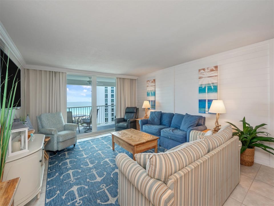 Unwind in your oceanfront living room where blue-toned furniture and coastal artwork create a soothing retreat with stunning balcony views.