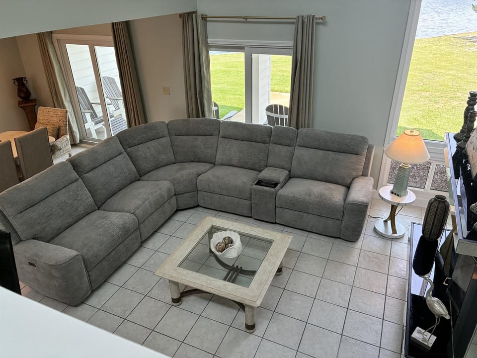 Sink into your spacious sectional sofa with stunning waterfront views through glass doors leading to your private outdoor seating area.