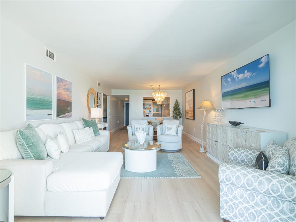 Sink into plush coastal comfort with soft sea-green accents and beach artwork surrounding you in this serene living space.
