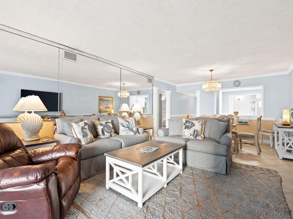 Sink into your spacious living area where coastal charm meets comfort - plush seating, nautical touches, and elegant chandeliers create your perfect retreat.