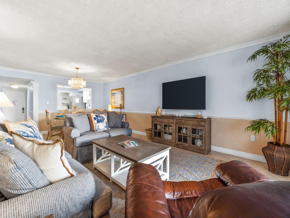 Unwind in your spacious living room with plush seating, smart TV, and elegant chandelier lighting for cozy evenings together.