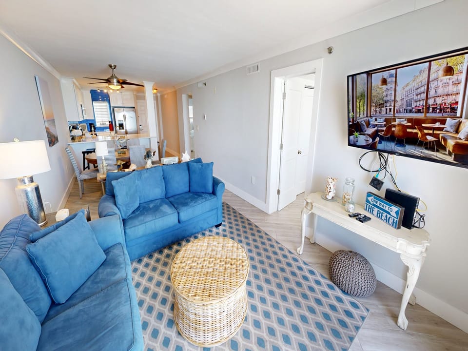 Sink into this bright coastal living space where blue sofas and beach-themed decor create your perfect oceanside retreat.