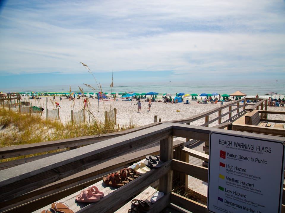 Beautiful white sand beach with colorful umbrellas and easy boardwalk access to pristine Gulf waters.
