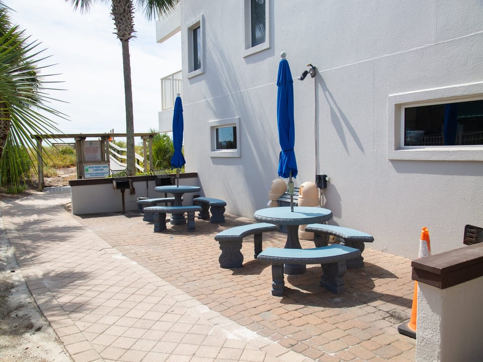 Relax on your private patio with comfortable seating and shade umbrellas, just steps from tropical palms and beach access.