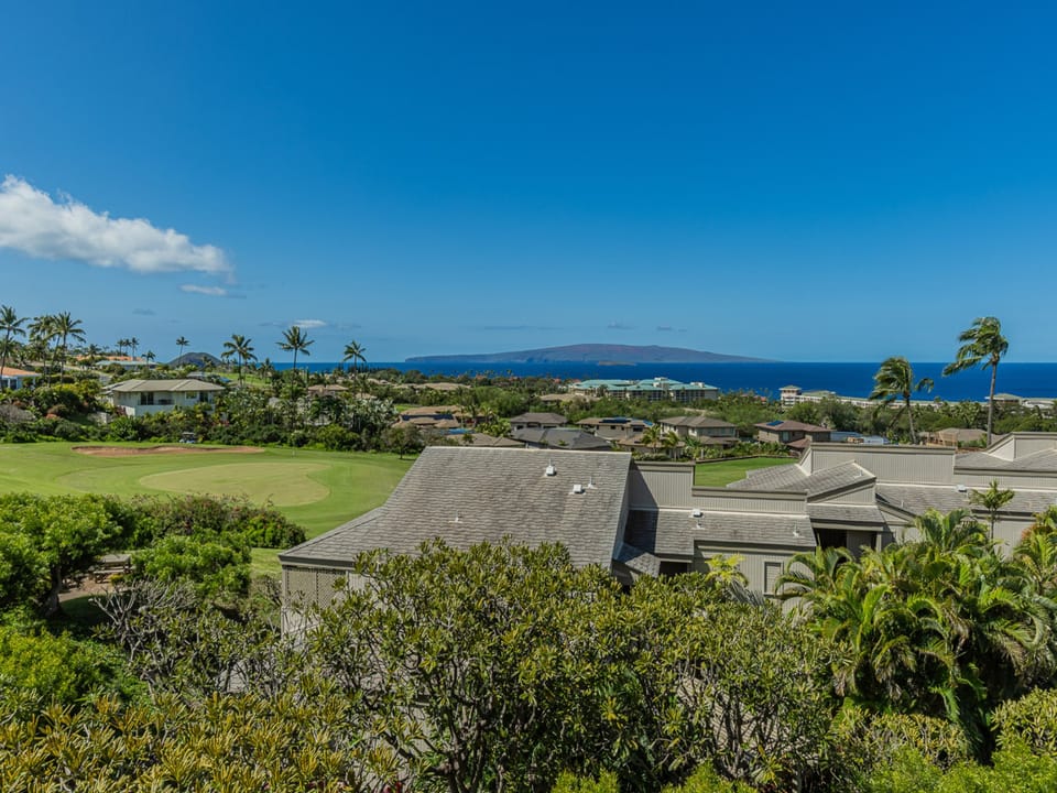 Stunning tropical view showcases the property amid lush golf course greens, with the ocean creating a picturesque Hawaiian setting.