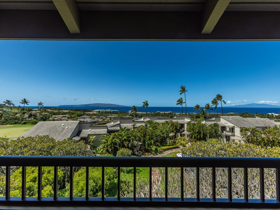 Sweeping ocean vistas and tropical palm trees create a stunning Hawaiian panorama from this elevated balcony perspective.