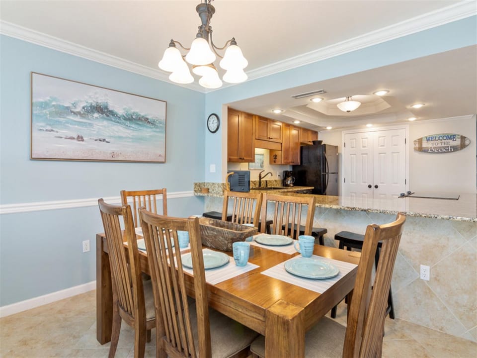 Gather around your spacious dining table where coastal artwork and soft blue walls create the perfect backdrop for memorable meals together.