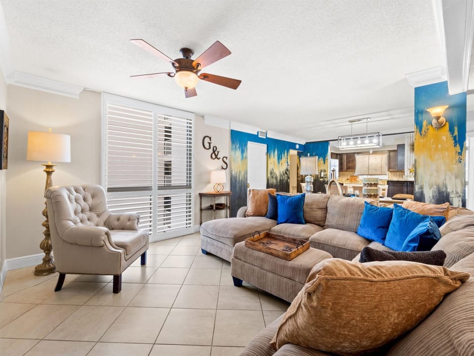 Unwind in your spacious living room featuring plush seating and vibrant coastal artwork that brings beachside tranquility indoors.