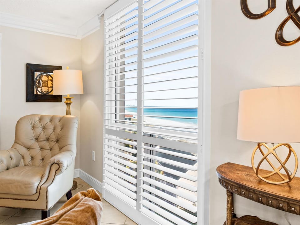 Sink into your private seating area where ocean breezes drift through elegant blinds, framing stunning sea views.