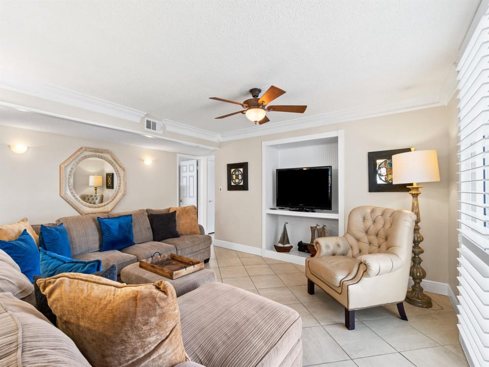 Unwind in your spacious living room with plush sectional seating, entertainment center, and coastal decor creating the perfect retreat atmosphere.