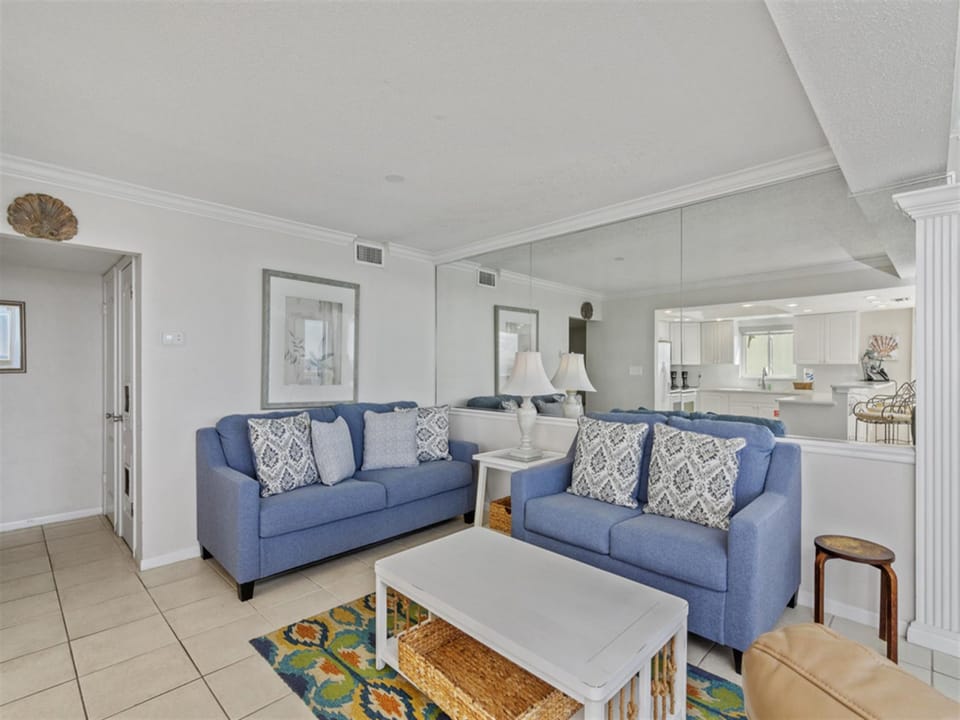 Relax in your spacious living room with comfortable blue sofas and elegant coastal decor, flowing seamlessly into the modern kitchen.