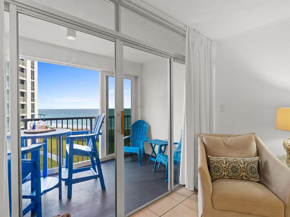 Relax in your bright living space while enjoying stunning ocean views from your private balcony with colorful beachside seating.