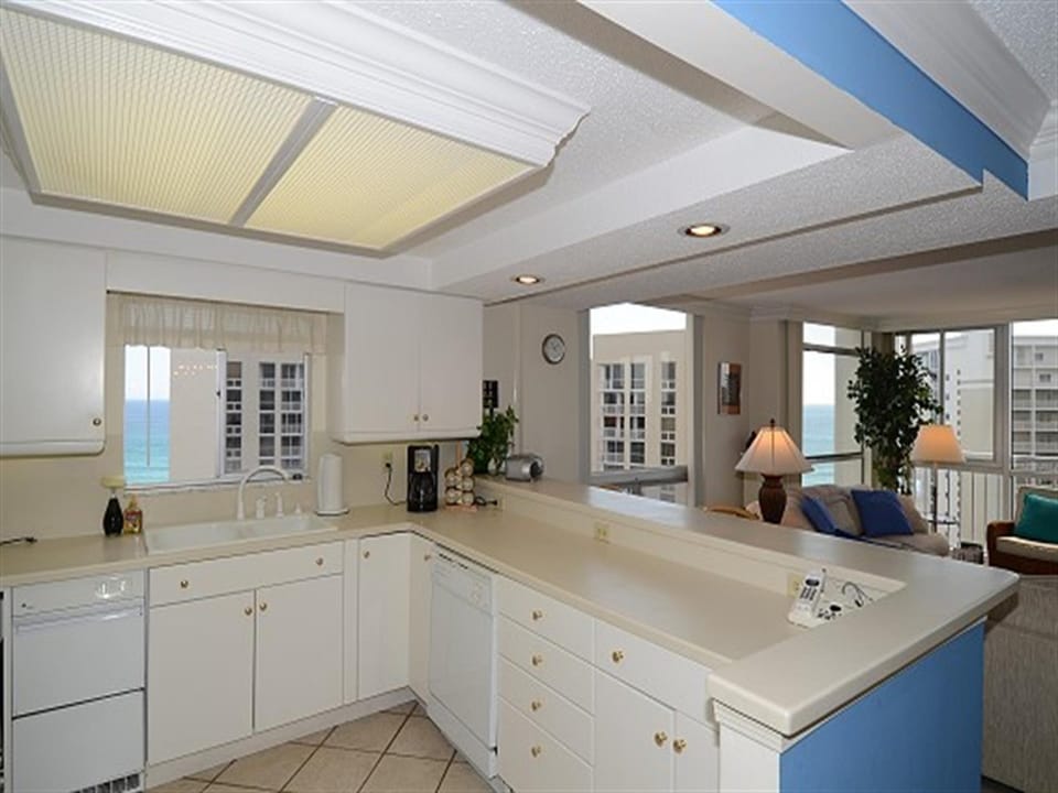 Your fully equipped kitchen awaits with pristine white cabinetry, spacious countertops, and stunning ocean views through charming glass-front cabinets.