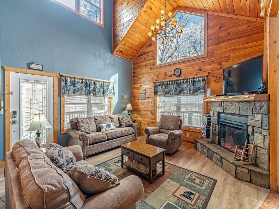 Cozy up in this rustic living room where warm wood beams meet stone fireplace comfort, perfect for your mountain retreat evenings.