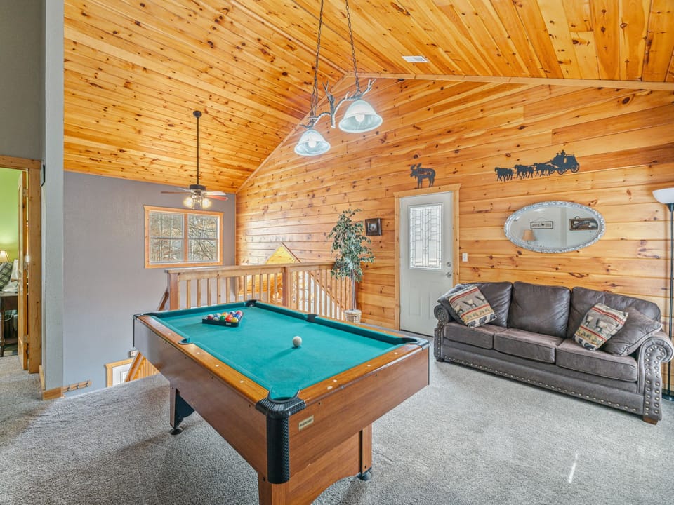Your game room awaits with a full-size pool table and cozy leather seating beneath warm wood ceilings for memorable evenings.