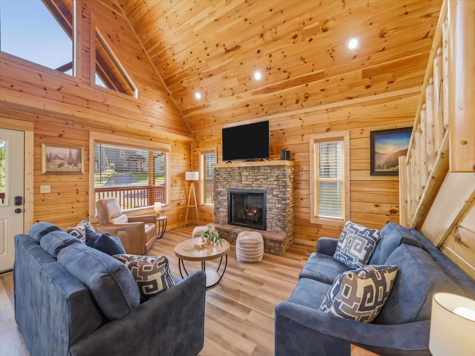 Sink into plush seating by your crackling fireplace in this warm wood-paneled living room, where mountain views and cozy comfort create your perfect retreat.