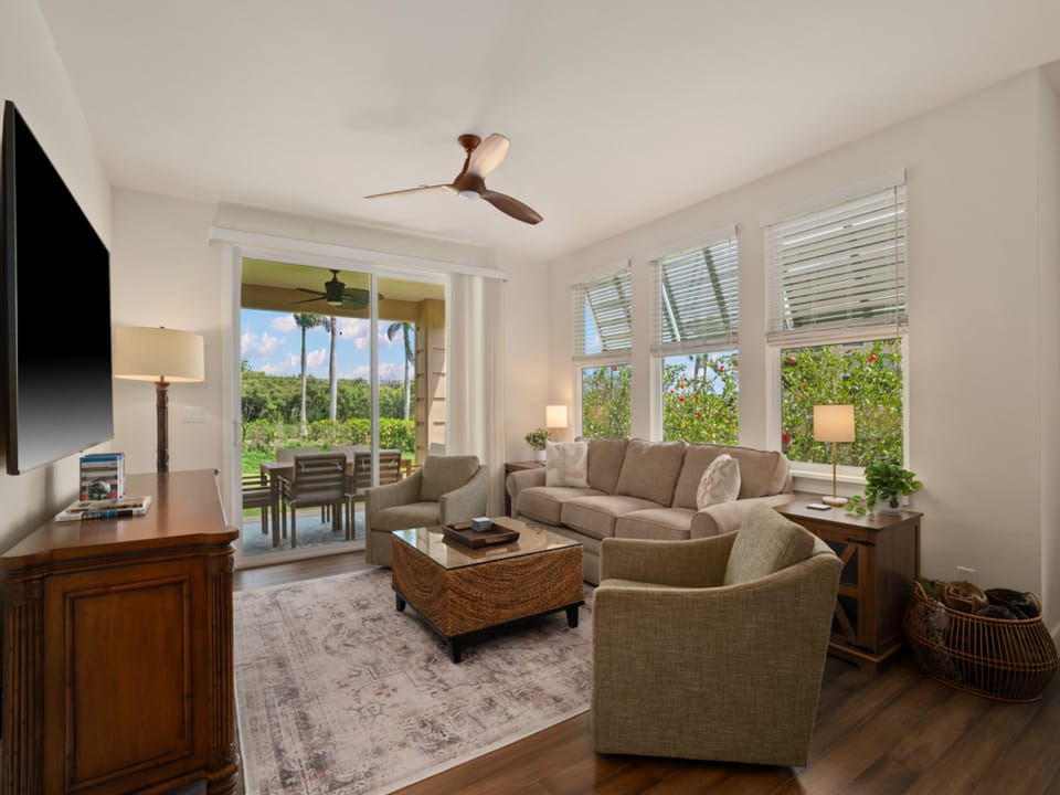 Unwind in this elegant living room where comfortable seating meets tropical paradise views through expansive windows.