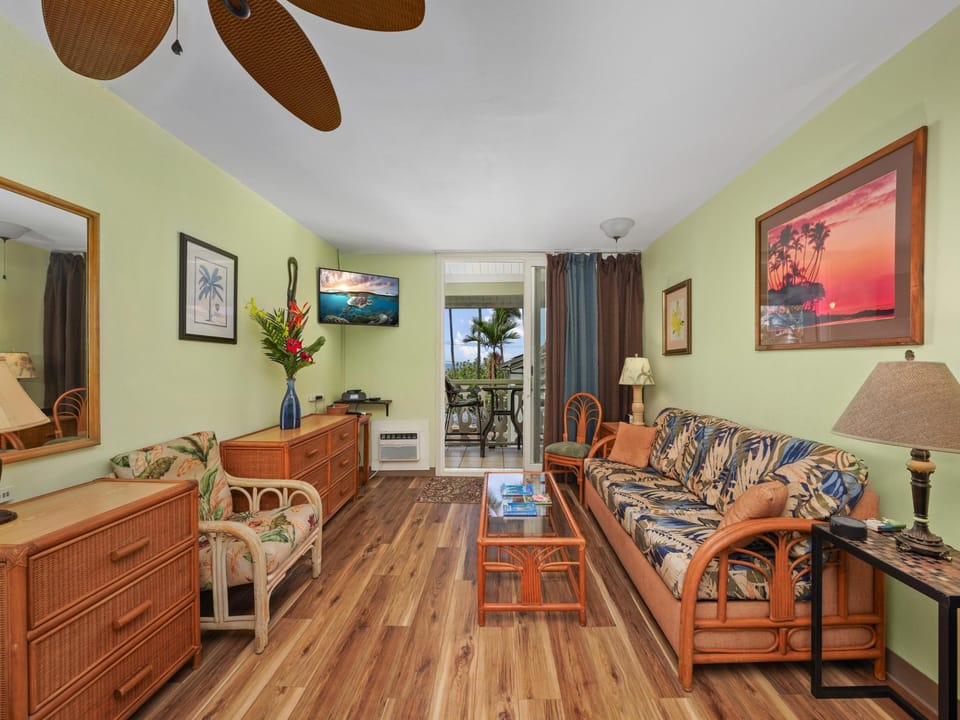 Unwind in your tropical-themed living room with vibrant Hawaiian artwork and comfortable rattan furniture overlooking your private balcony.