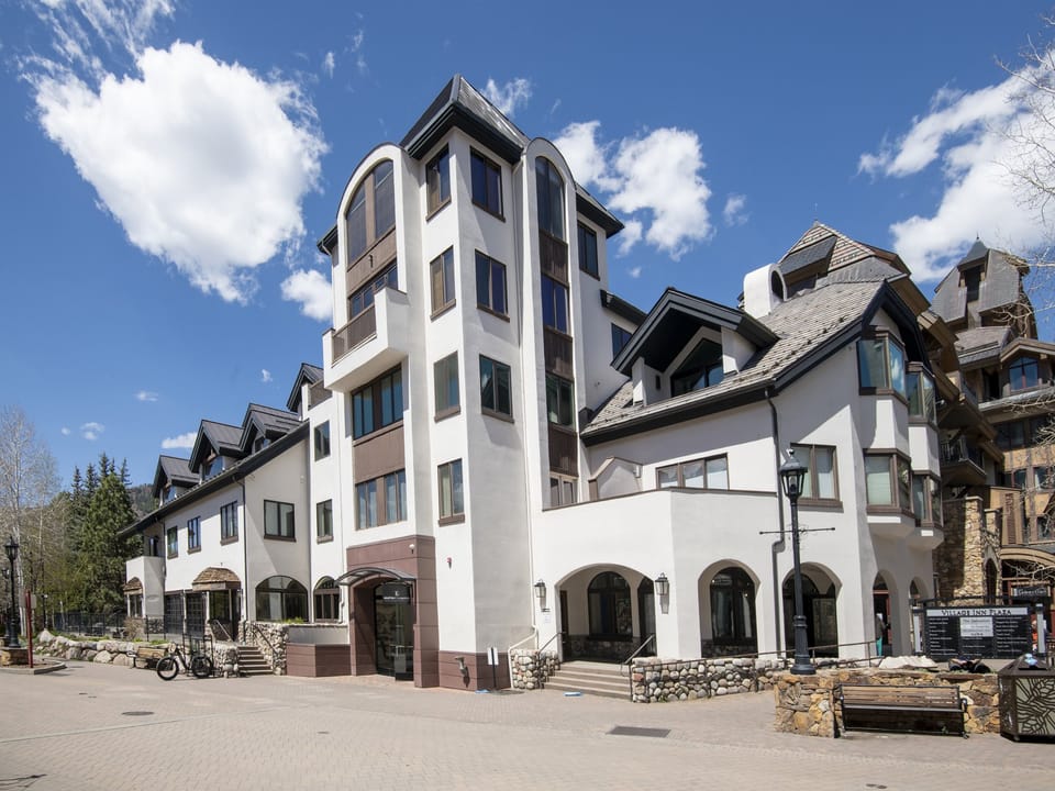 A distinctive alpine-style building with striking architecture and arched entryways serves as the main property structure in a picturesque mountain setting.