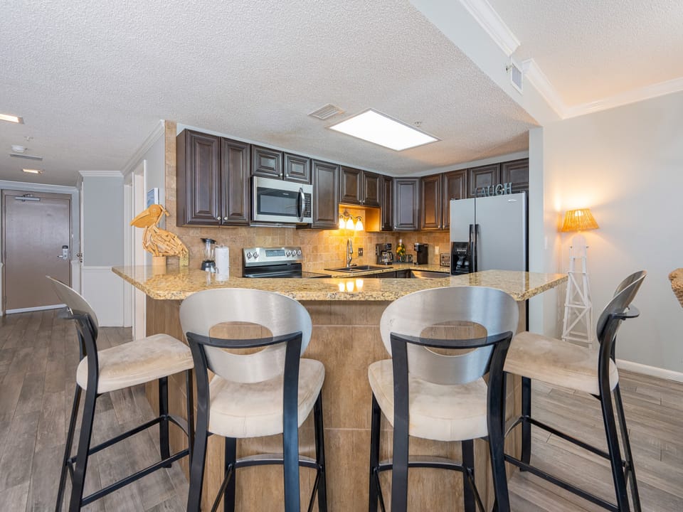 Warm under-cabinet lamps invite you to gather around the breakfast bar in the kitchen area