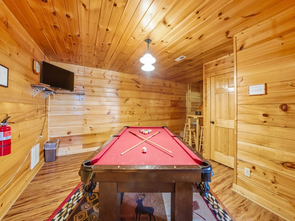 Challenge friends to a game in your private billiards room, featuring warm wood walls and entertainment center for cozy mountain evenings.