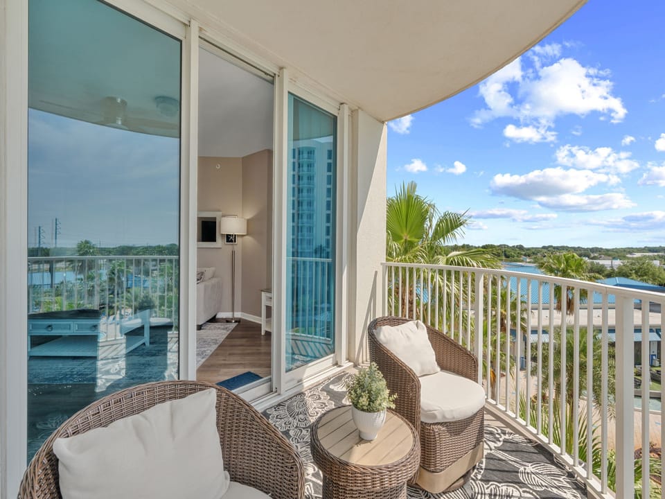 Unwind in your private balcony retreat with cozy wicker seating, tropical palms, and sweeping water views—your perfect spot to soak up the sunshine and serene scenery.