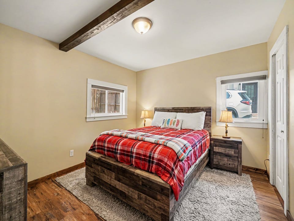Sink into the plush bed with its vibrant plaid duvet and rest your head under charming rustic beams. Warm wood tones and soft lighting create a cozy retreat for your mountain escape.