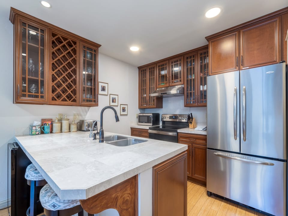 Your gourmet kitchen features elegant wood cabinetry, marble countertops, stainless steel appliances, and a charming wine rack—perfect for preparing meals and gathering with loved ones in a warm, welcoming space.