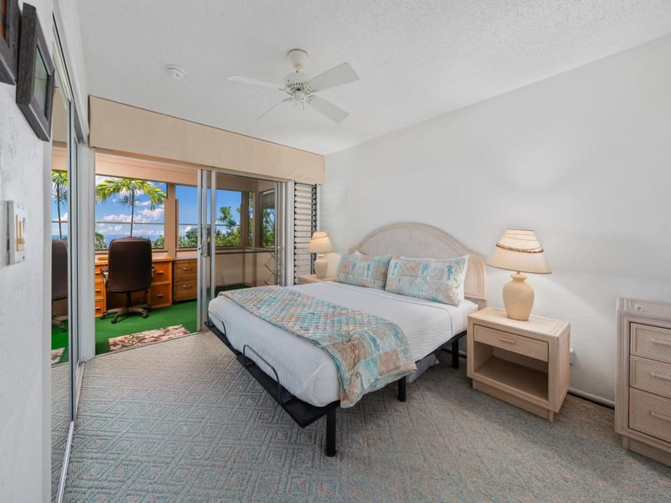 Your serene bedroom features coastal-inspired linens and opens onto a private outdoor workspace with tropical views, creating a peaceful retreat for rest and relaxation.