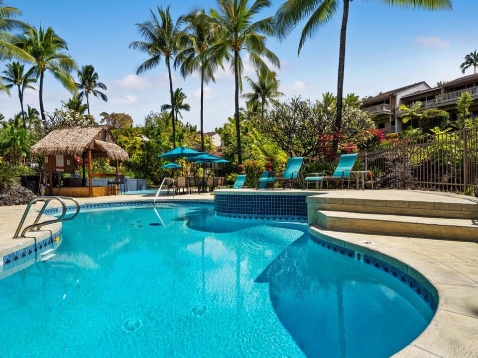 Your tropical oasis awaits with sparkling turquoise waters, swaying palms, and inviting lounge chairs perfect for soaking up the Hawaiian sunshine.