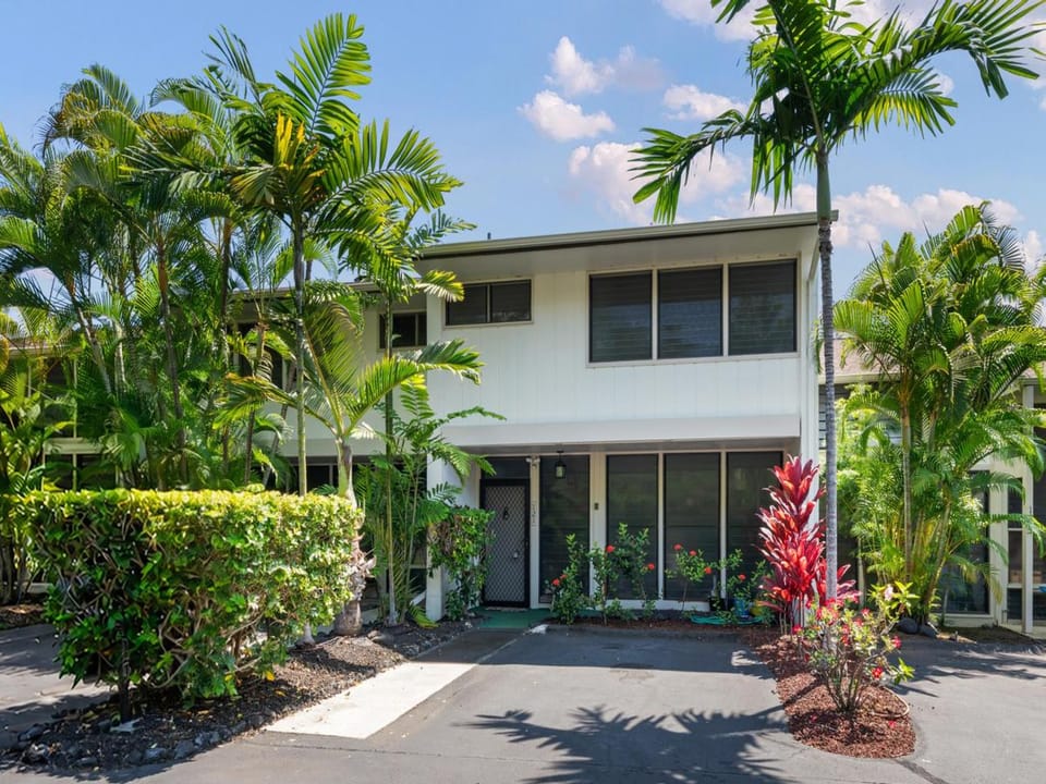A tropical resort property surrounded by lush palm trees and vibrant landscaping under a bright, sunny sky.