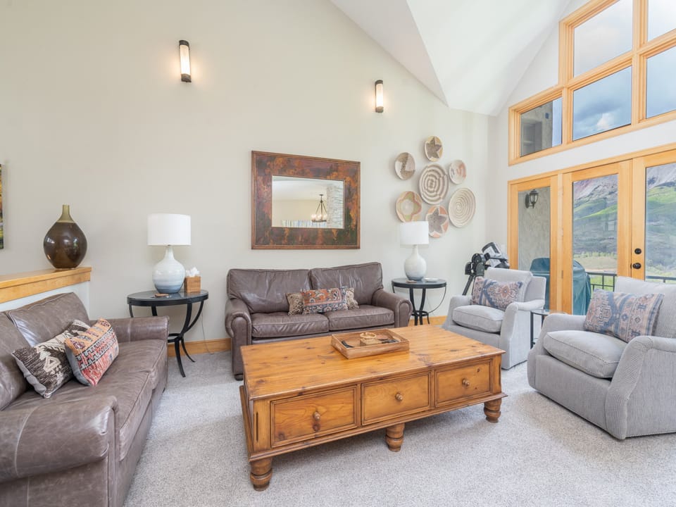 Relax in your spacious living room with soaring cathedral ceilings, comfortable seating, and stunning mountain views through expansive windows. Warm wood accents and thoughtful decor create your perfect home base for adventure.