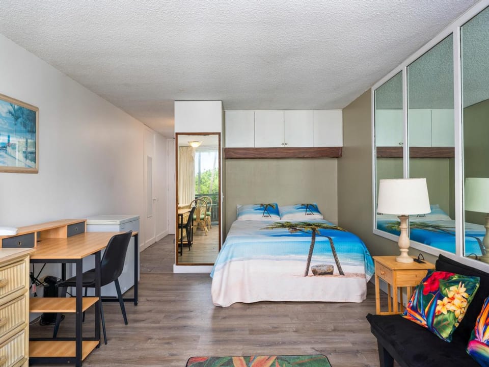 Your bright studio features a Murphy bed with tropical beach linens, a dining workspace, and mirrored wardrobes. Peek through to your private balcony where morning coffee awaits.