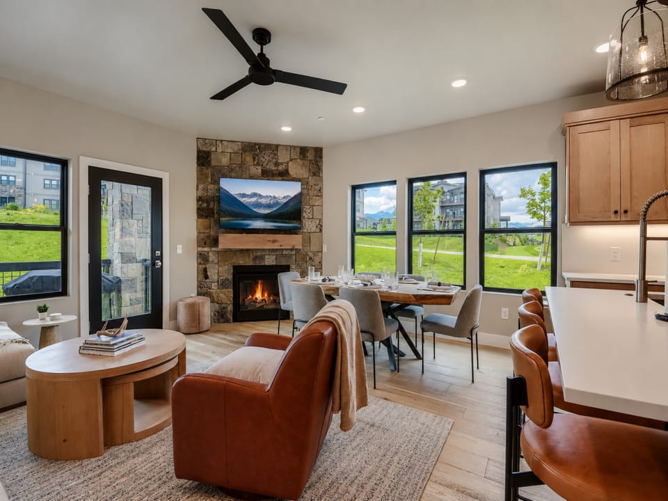 Gather around the stone fireplace or enjoy meals at the dining table while soaking in mountain views through expansive windows. The open-concept layout connects your living, dining, and kitchen spaces seamlessly for effortless relaxation.