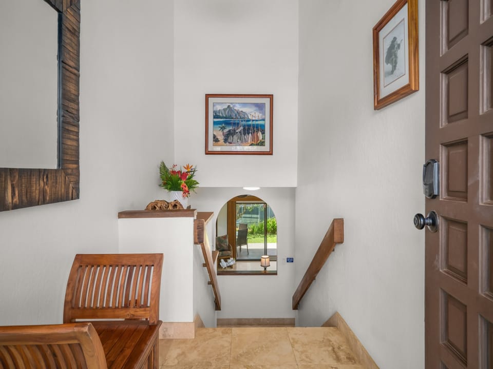 A charming entryway welcomes you with warm wooden accents, cozy seating, and thoughtful touches like local artwork and tropical blooms to start your island escape.