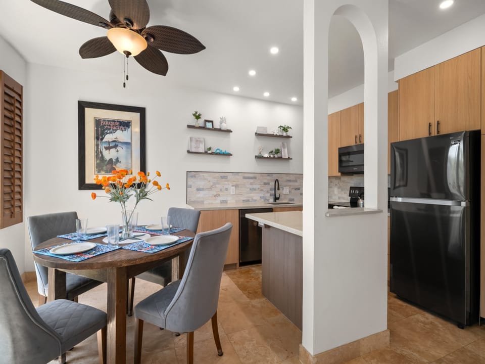 Gather around this inviting dining space where a coastal inspired ceiling fan and bright decor set a relaxed tone. Your fully equipped kitchen awaits, seamlessly blending style with modern convenience.