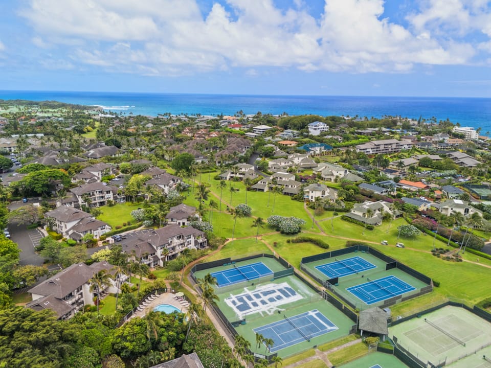 This tropical resort community features tennis courts, a swimming pool, and lush green spaces, all nestled between verdant landscaping and the sparkling Pacific coastline.