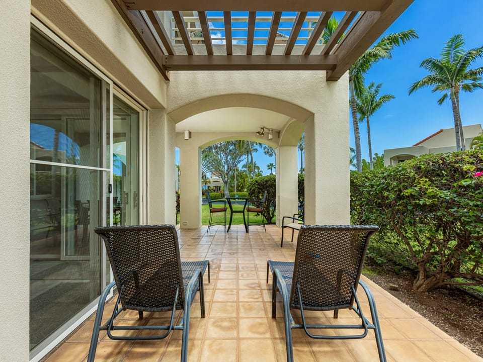 Your private patio offers a peaceful retreat with comfortable seating under a pergola, framed by lush palms and tropical greenery. Relax outdoors and enjoy the serene garden setting.