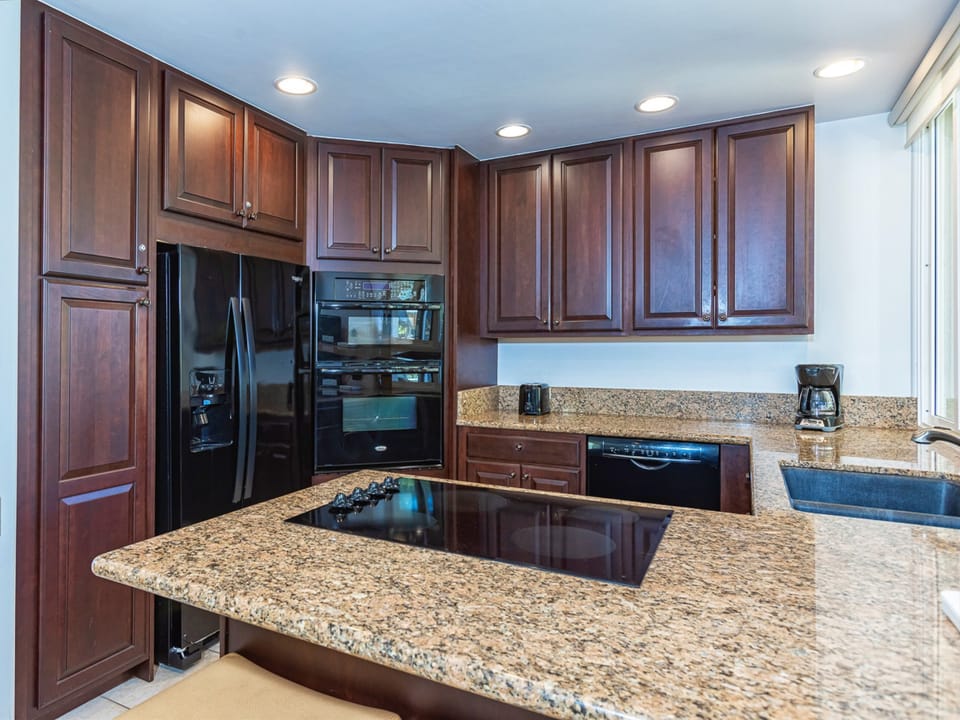 Your gourmet kitchen awaits with gleaming granite countertops, rich wood cabinetry, perfect for preparing meals by the window.